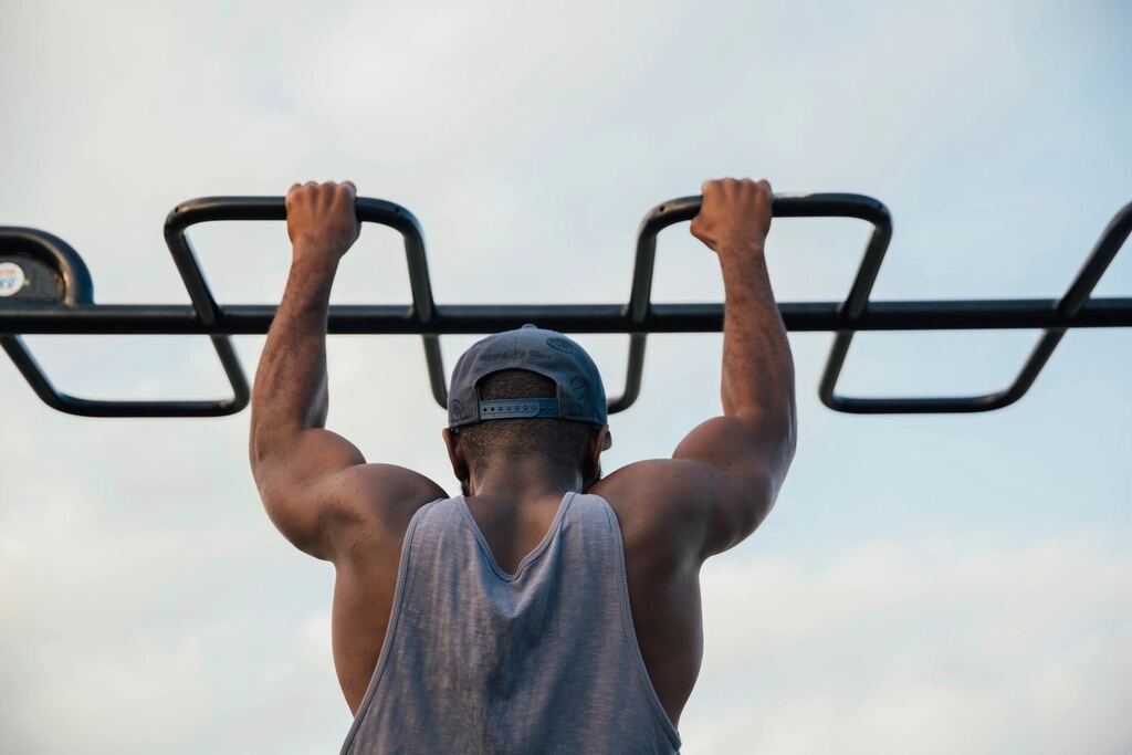 A man doing pull-ups on an outdoor bar